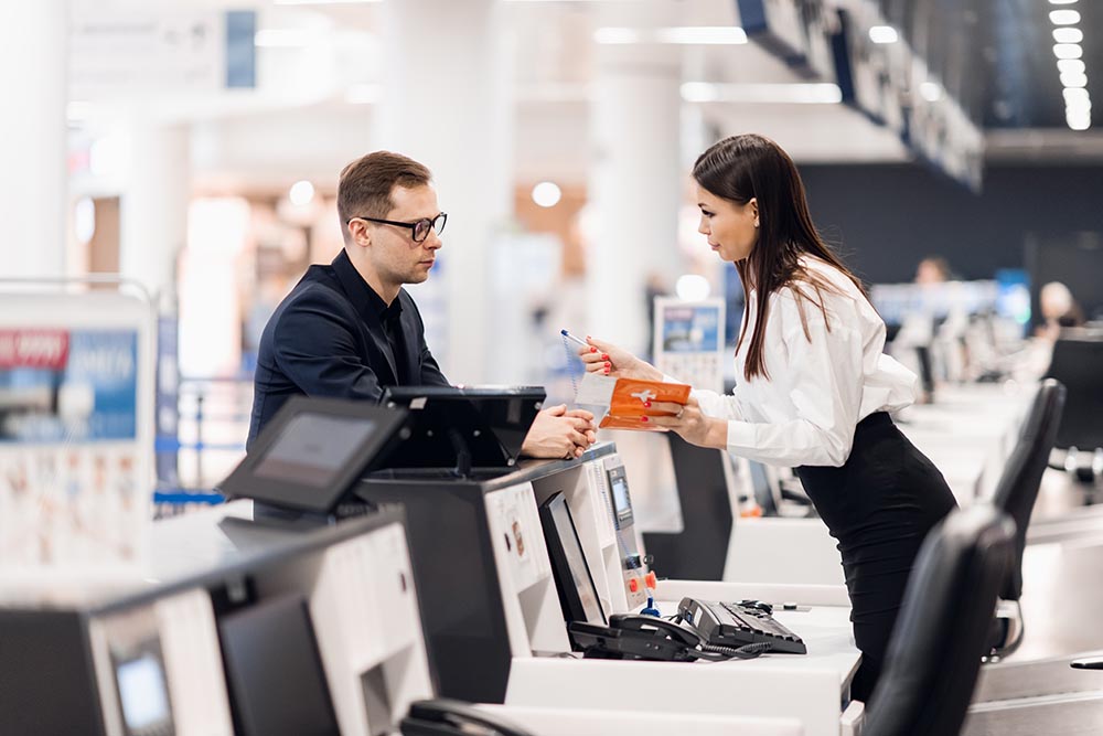 Frau am Flughafen, die die Bordkarte von einem Geschäftsreisenden entgegennimmt