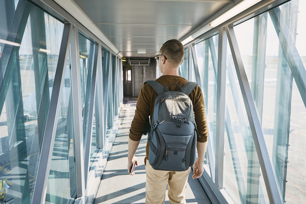 Geschäftsreisender mit Rucksack geht über den Fluggang zum Flugzeug.