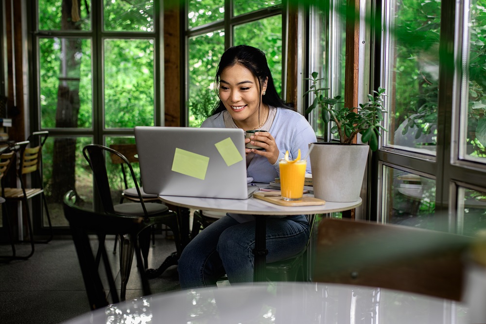 Remote-Arbeiter, der im Café umgeben von Grün arbeitet
