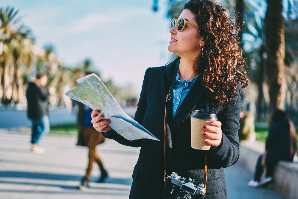 Mädchen besucht eine Stadt mit Kamera, Kaffee und Karte in der Hand.