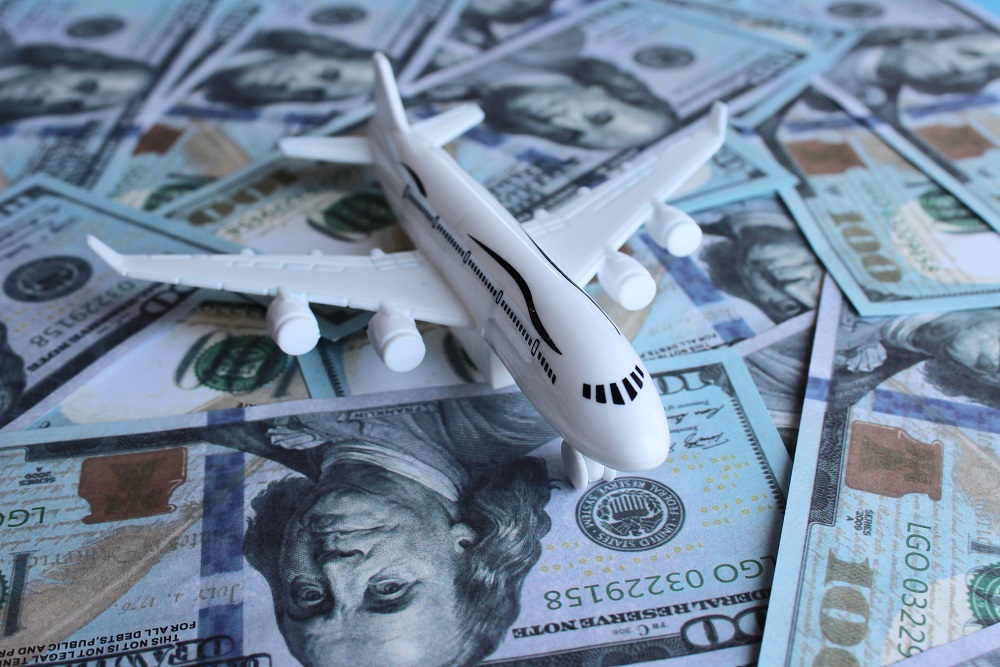 Dollarnoten mit Reisepass und Spielzeugflugzeug