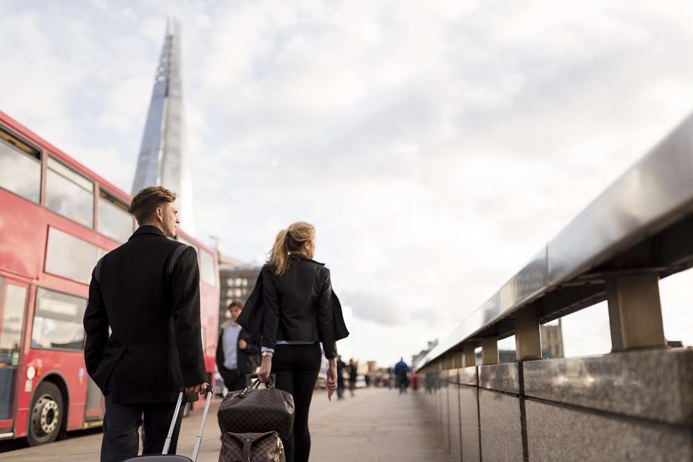 Zwei Geschäftsleute neben einem Bus mit Gepäck in London