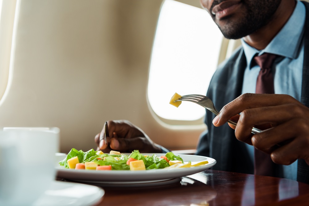 Geschäftsreisender isst einen Salat in der Business Class eines Flugzeugs