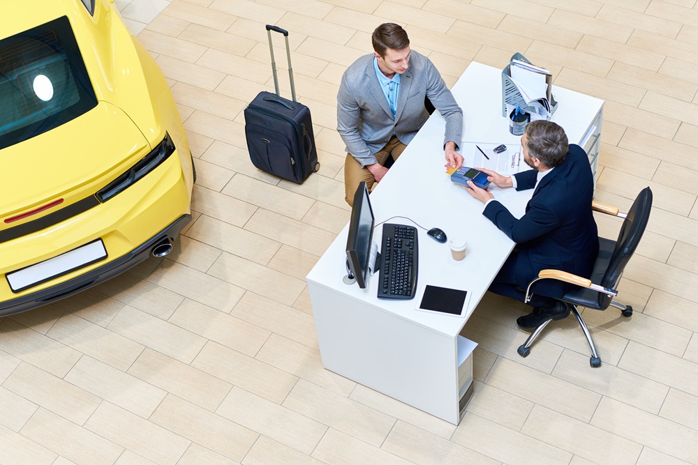 Businessman Paying for Car Geschäftsreisender bei der Autovermietung bekommt Schlüssel