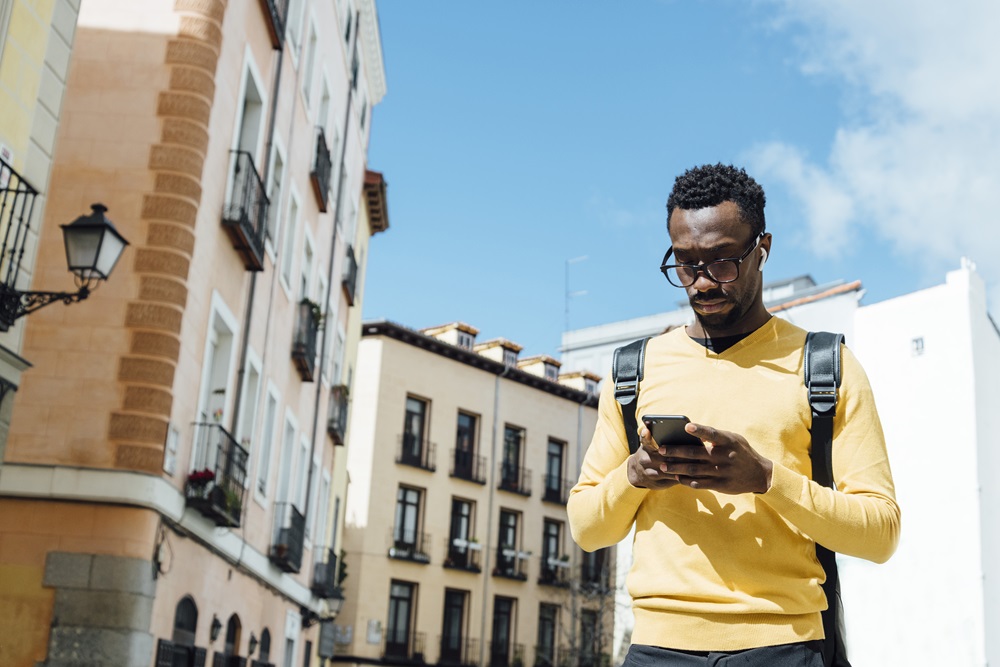 Geschäftsreisender benutzt sein Handy, während er durch die Straßen von Madrid läuft.