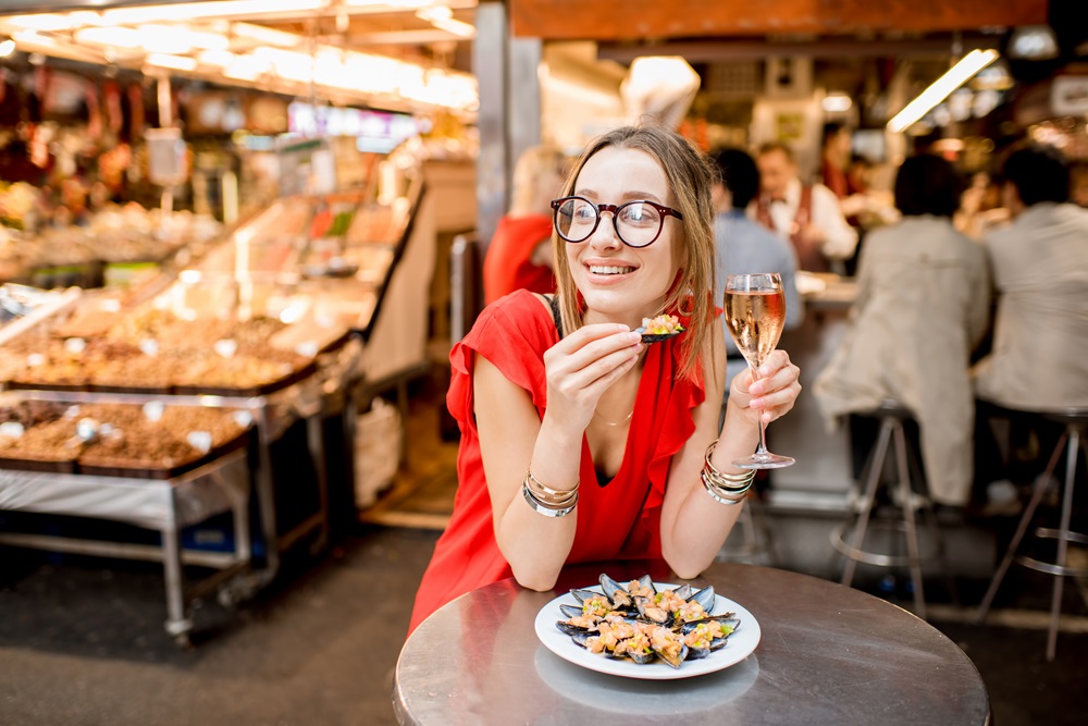 Woman eating mussels at the food market Geschäftsreisender isst Tapas auf dem Markt in Madrid.