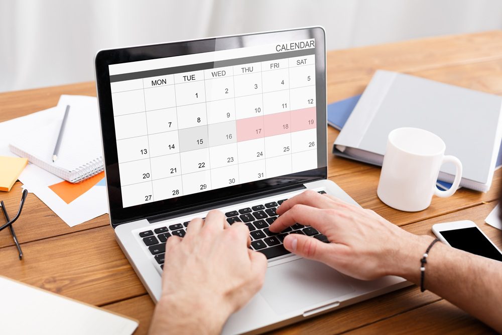 werknemer met laptop die naar de kalender op zijn laptop kijkt