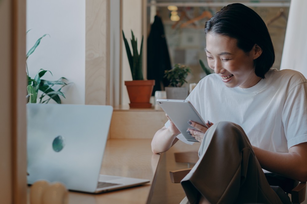 Asian woman looking at tablet with a smile