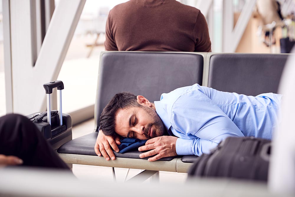 Man in  business clothes sleeping on airport chairs on a layover