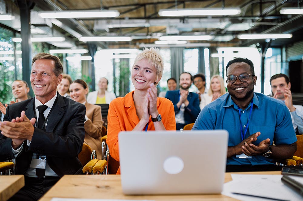 Three business people at a conference with a laptop