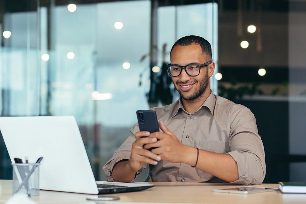 Man with glasses looking at cellphone in the office