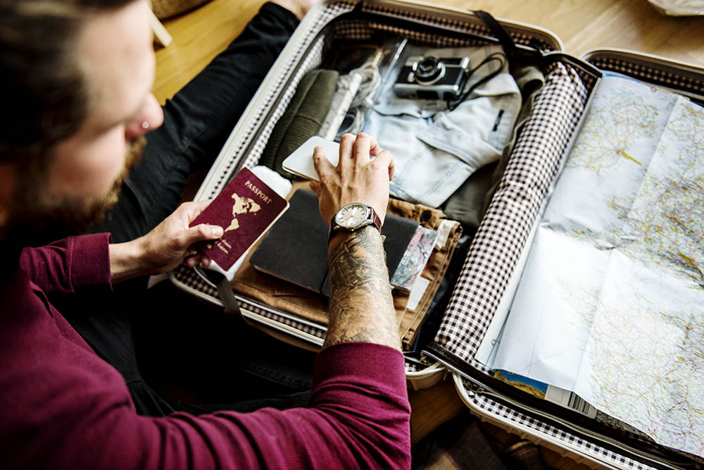 Man packing suitcase with passport in hand