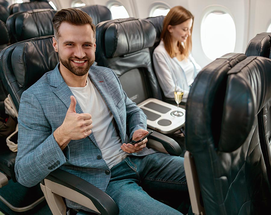 Man in airline seat giving thumbs up