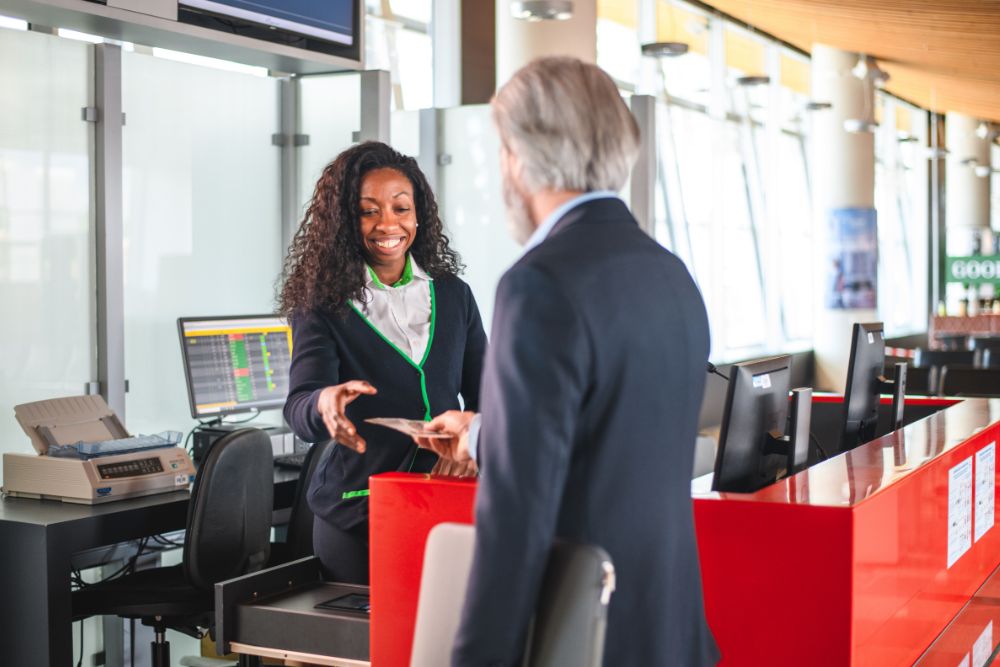 Woman working at airport collecting boarding pass from business traveler