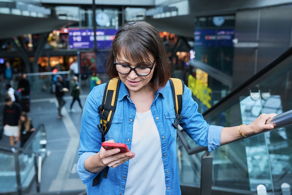 woman on escalator looking at cell phone corporate travel trends