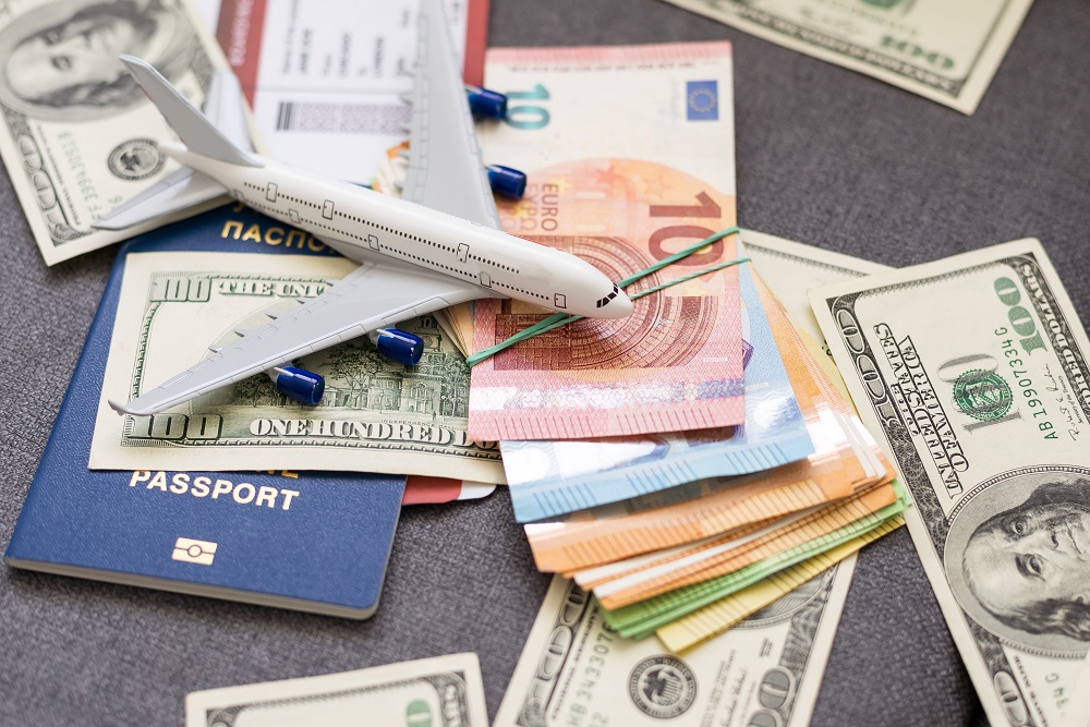 Dollar bills and euros with a passport and a plane