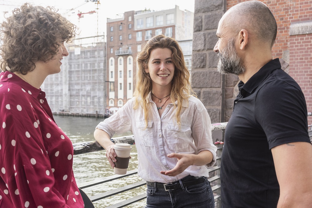 Team members talking on bridge with coffee cup
