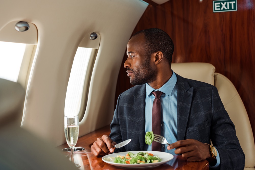 Business man eating in business class and looking out the window