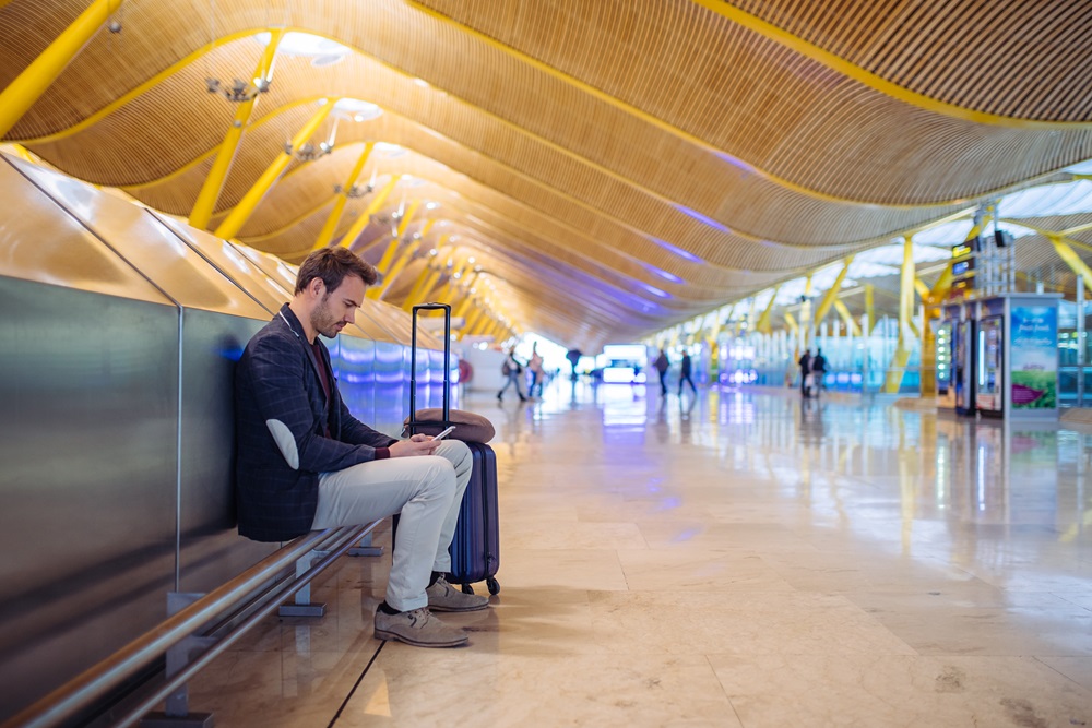 Business traveler on layover in the airport using cell phone