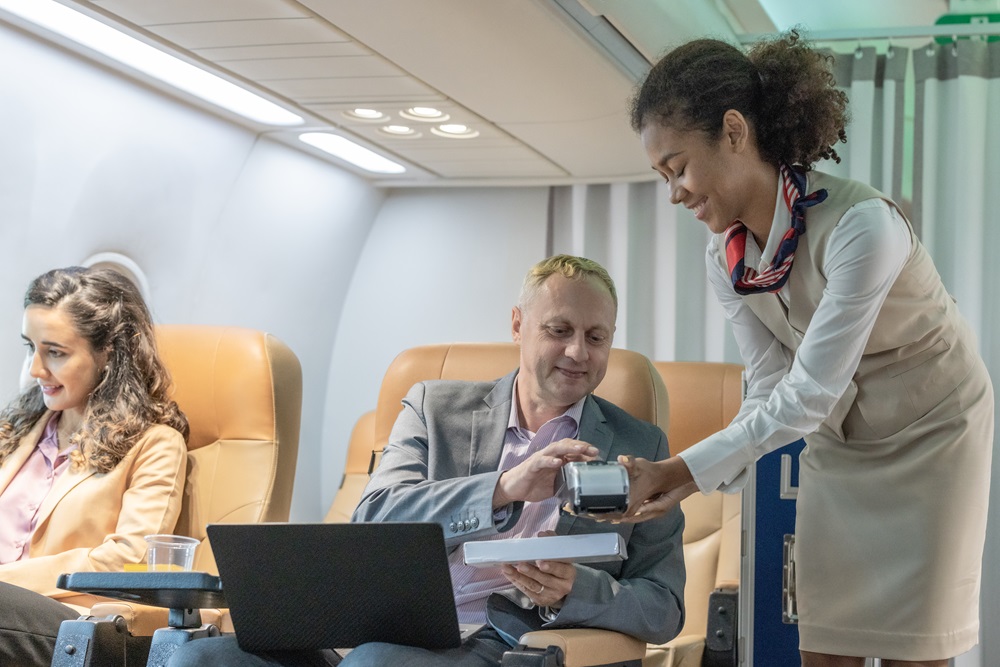 Man in business class working from the plane as he orders from a flight attendant