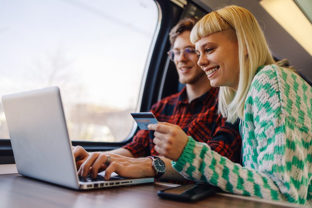 A cheerful young couple commuting by train and ordering online. Travelers booking on a train