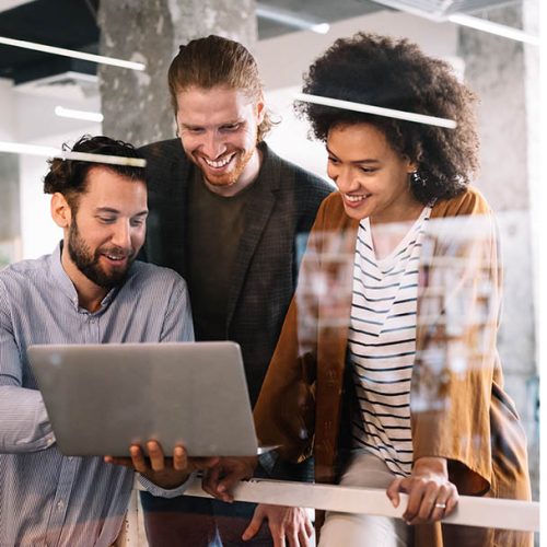 Three people looking at a laptop screen with smile