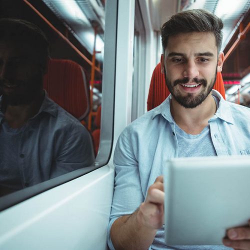 Smiling executive using digital tablet travelling in train